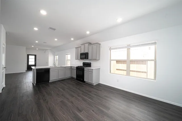 a large kitchen with a center island wooden floor stainless steel appliances and a window