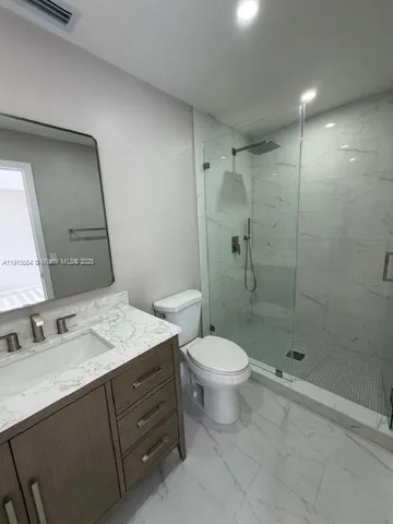 a bathroom with a shower sink vanity mirror and toilet