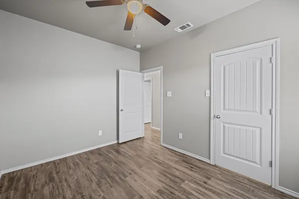 an empty room with wooden floor cabinet and windows
