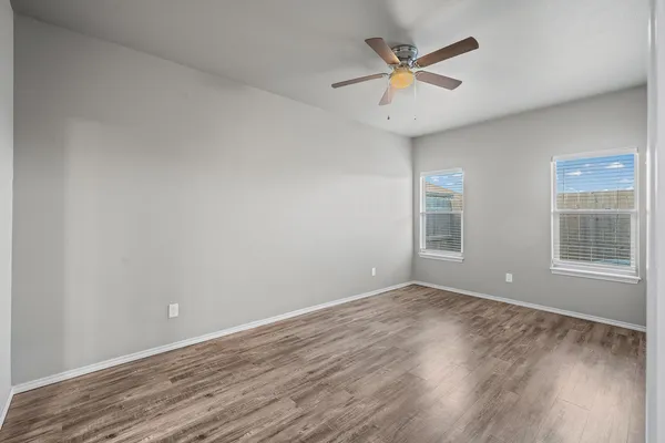 an empty room with wooden floor and windows