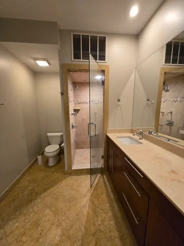 a spacious bathroom with a granite countertop sink a toilet a mirror and shower