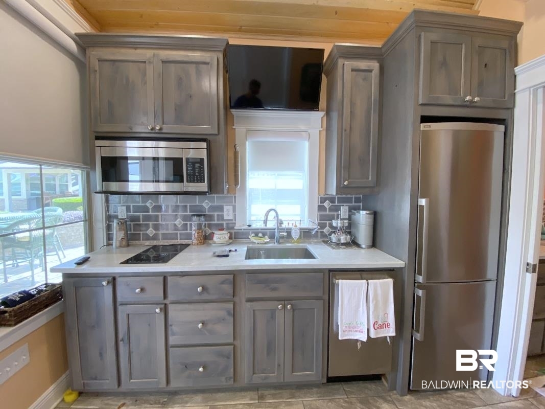 28888 Canal Road, Unit 32 Orange Beach, AL 36561 - Photo 7 of 29 Kitchen with stainless steel appliances, decorative backsplash, light stone counters, and gray cabinets