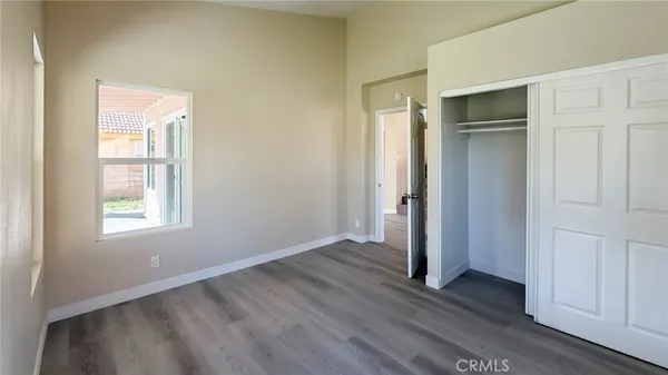 an empty room with wooden floor and closet area