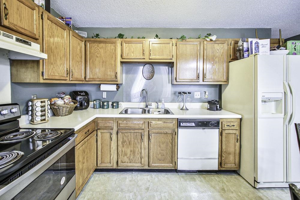 Kitchen featuring a textured ceiling, sink, and white appliances