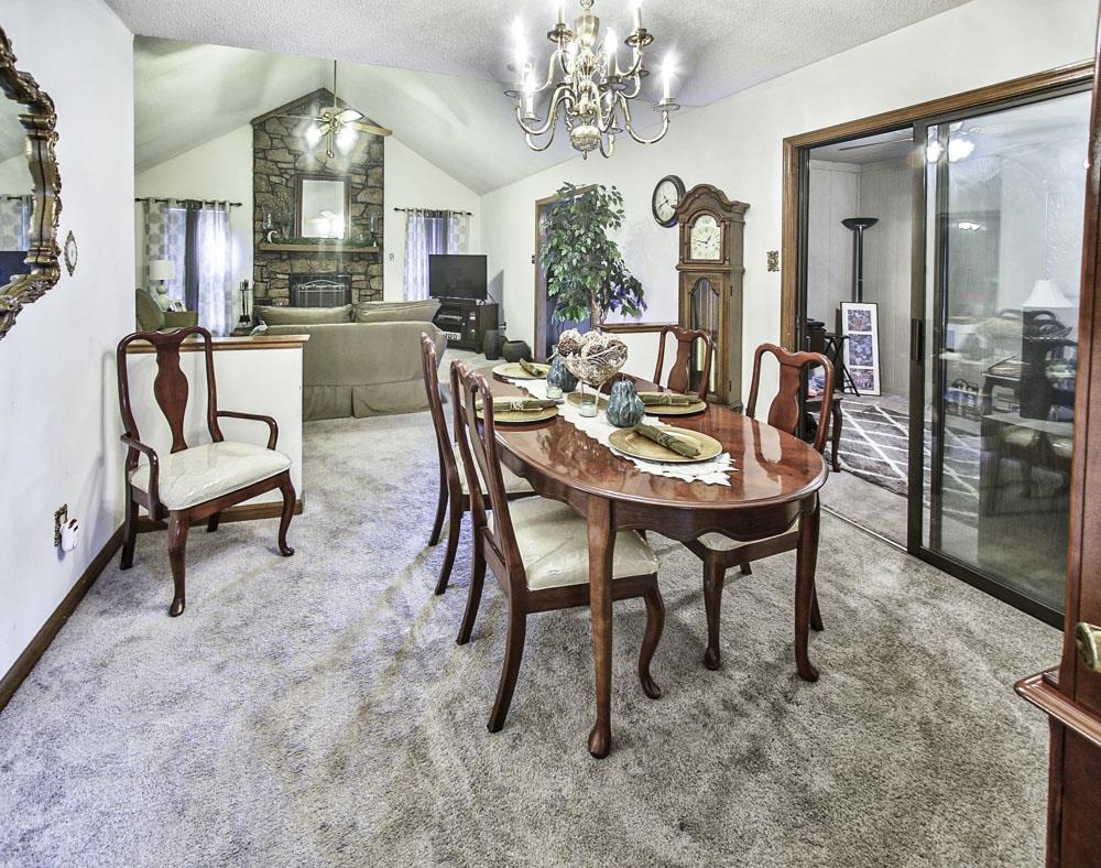 4352 Cloudburst Road Memphis, TN 38141 - Photo 8 of 21 Carpeted dining space featuring a stone fireplace, lofted ceiling, a textured ceiling, and ceiling fan with notable chandelier