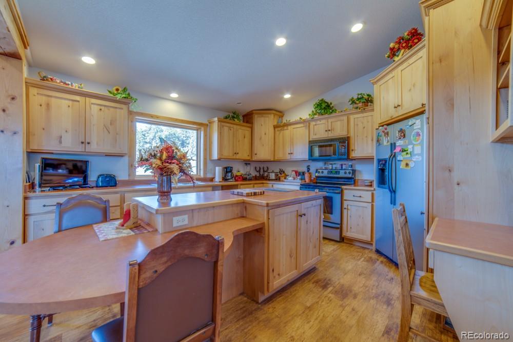 8615 Highway 165 Rye, CO 81069 - Photo 14 of 37 a kitchen with stainless steel appliances granite countertop a refrigerator a sink dishwasher a stove and a dining table with wooden floor