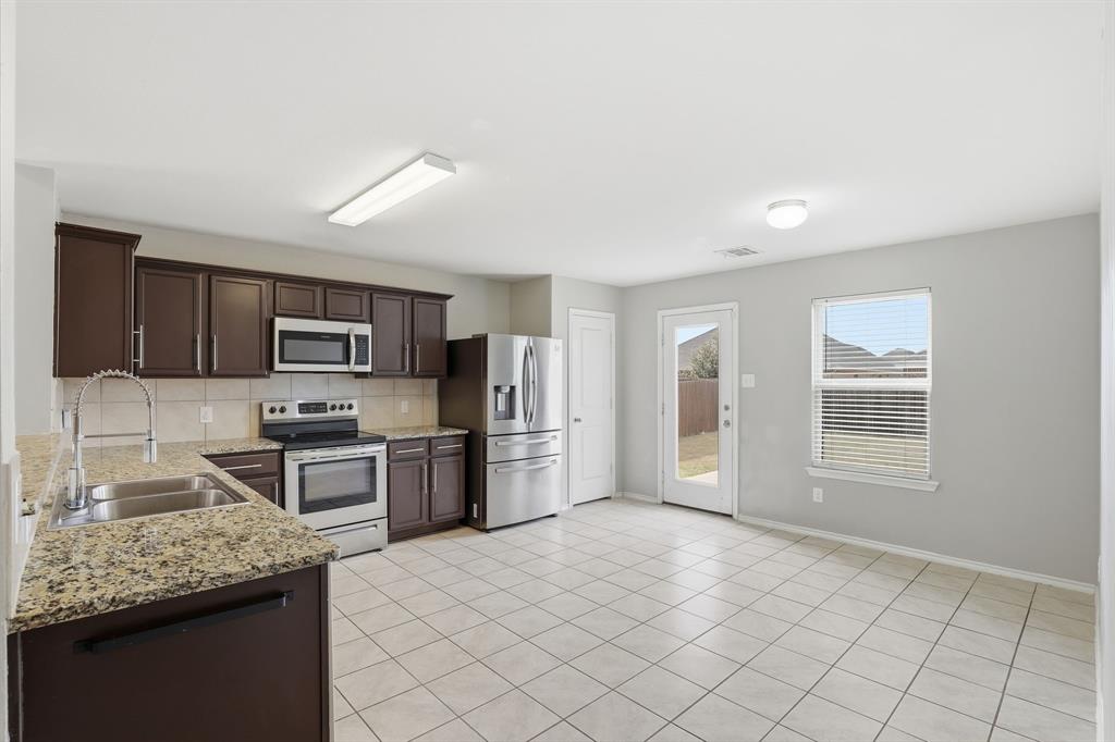 3035 Seth Lane Forney, TX 75126 - Photo 11 of 31 a kitchen with stainless steel appliances granite countertop a sink stove and refrigerator