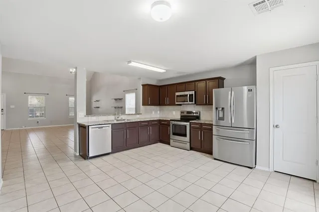 a kitchen with stainless steel appliances granite countertop a refrigerator sink and stove