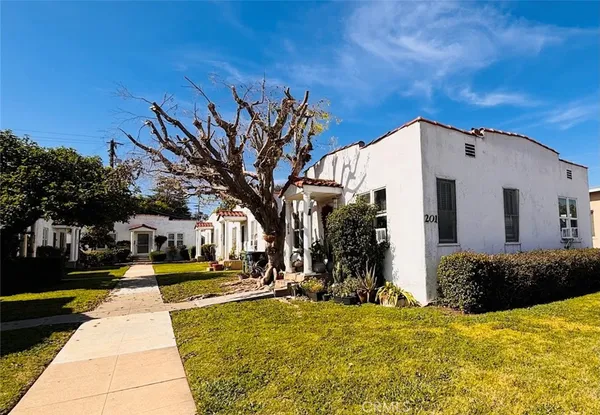 a view of a white house with a large tree