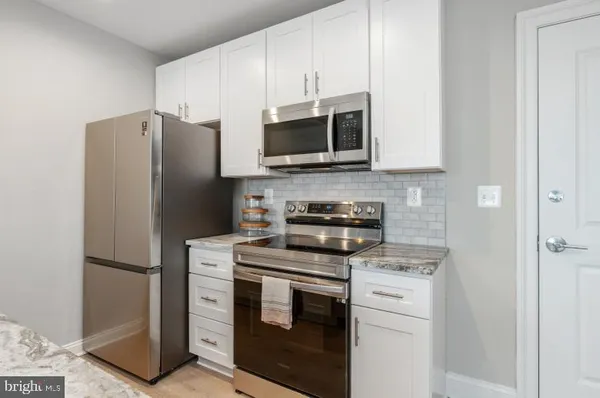 a kitchen with stainless steel appliances white cabinets and a refrigerator