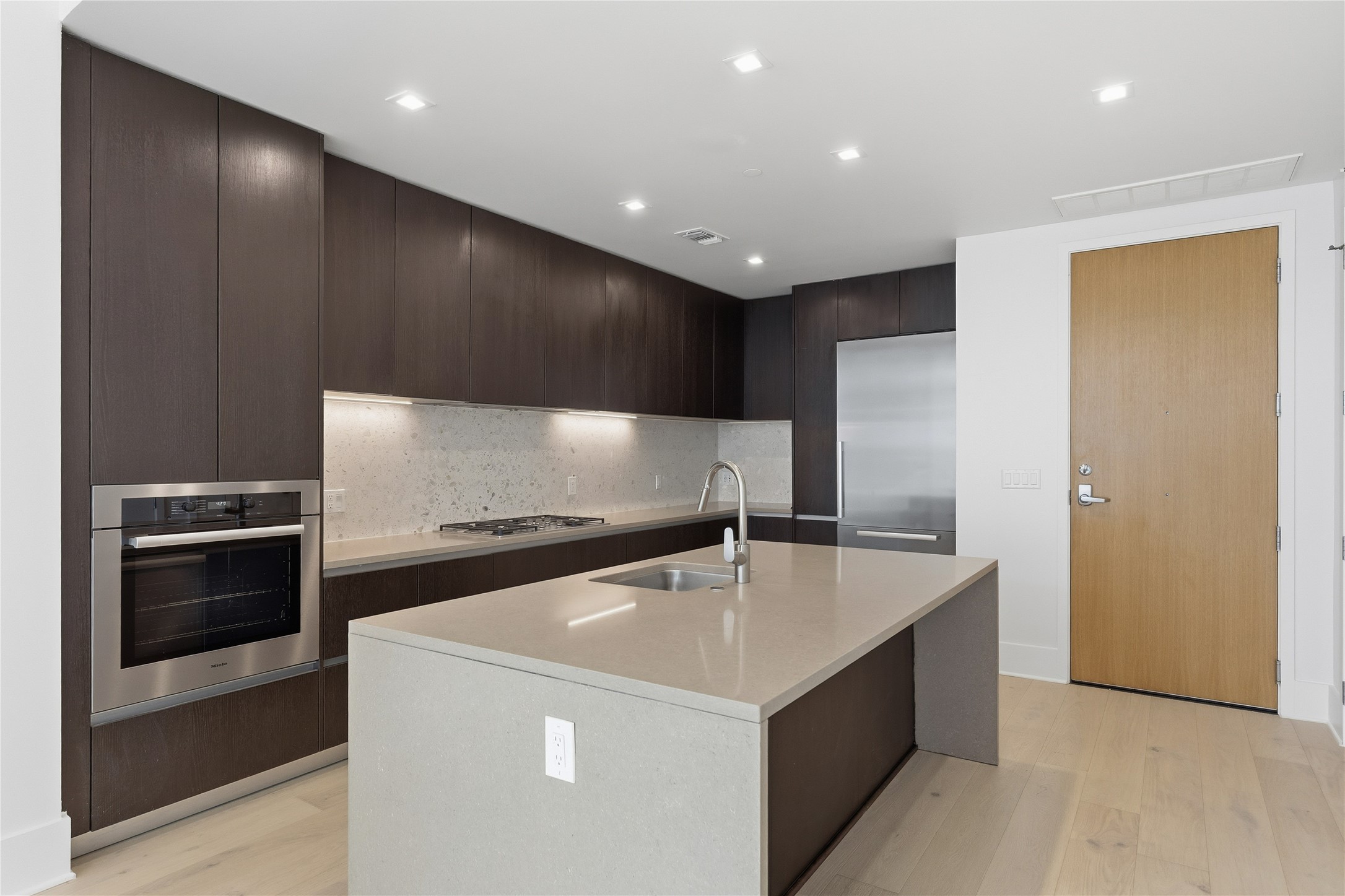 501 West Avenue, Unit 802 Austin, TX 78701 - Photo 2 of 40 Kitchen featuring modern cabinets, appliances with stainless steel finishes, light stone counters, light wood-style flooring, and recessed lighting