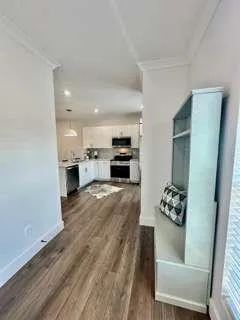 a open kitchen with kitchen island a stove a sink dishwasher and a dining table with wooden floor