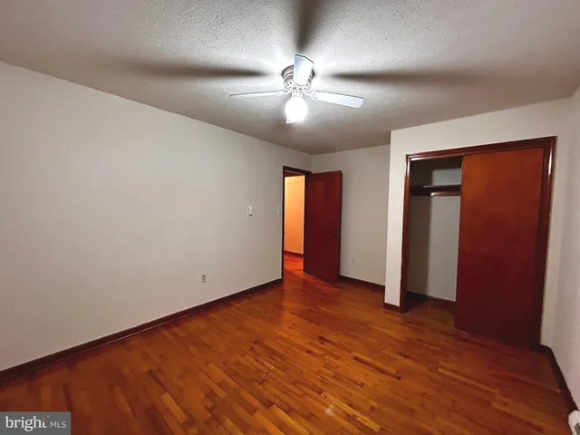 an empty room with wooden floor and ceiling fan