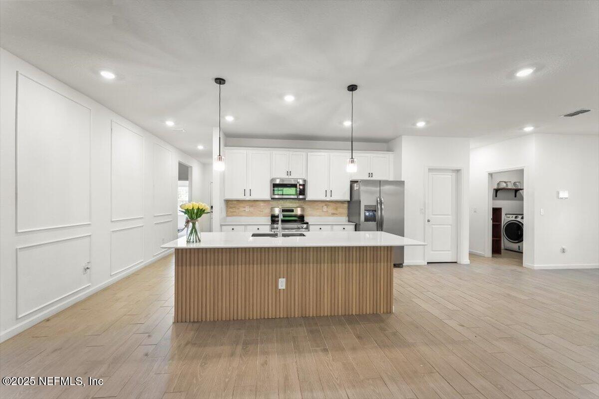 1598 Lachlan Circle Jacksonville, FL 32218 - Photo 5 of 38 a large kitchen with kitchen island a sink a center island stainless steel appliances and a fireplace
