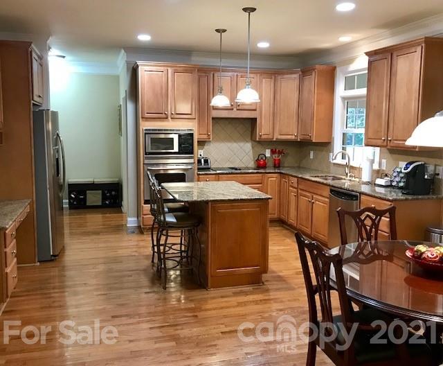 1912 Riverbank Road Waxhaw, NC 28173 - Photo 7 of 19 a kitchen with stainless steel appliances granite countertop a stove a refrigerator a sink a dining table and chairs with wooden floor