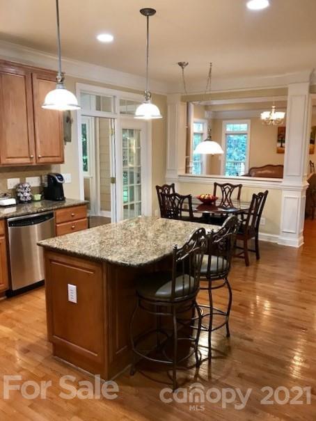 1912 Riverbank Road Waxhaw, NC 28173 - Photo 8 of 19 an open kitchen with granite countertop a stove a sink a dining table and chairs with wooden floor