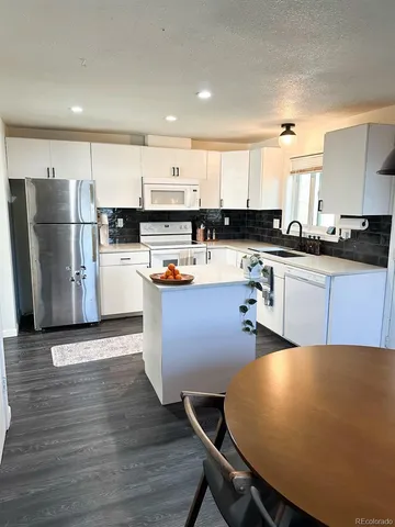 a kitchen with stainless steel appliances granite countertop a refrigerator a sink dishwasher a stove top oven a counter space and cabinets