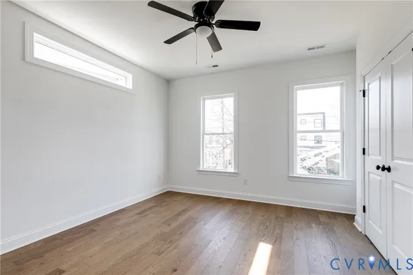 a view of an empty room with wooden floor and a window