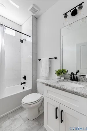 a bathroom with a granite countertop sink mirror vanity and toilet