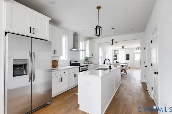 a kitchen with stainless steel appliances a refrigerator a sink a stove and white cabinets