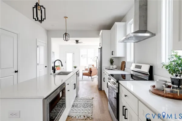 a kitchen with stove a sink dishwasher a refrigerator and a dining table with wooden floor