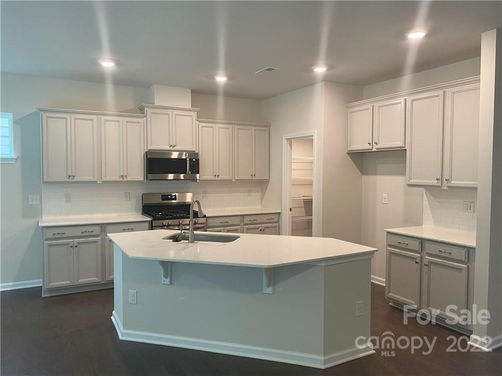 4043 Oakmere Road, Unit 953 Waxhaw, NC 28173 - Photo 6 of 21 a kitchen with kitchen island a sink a stove a refrigerator and white cabinets