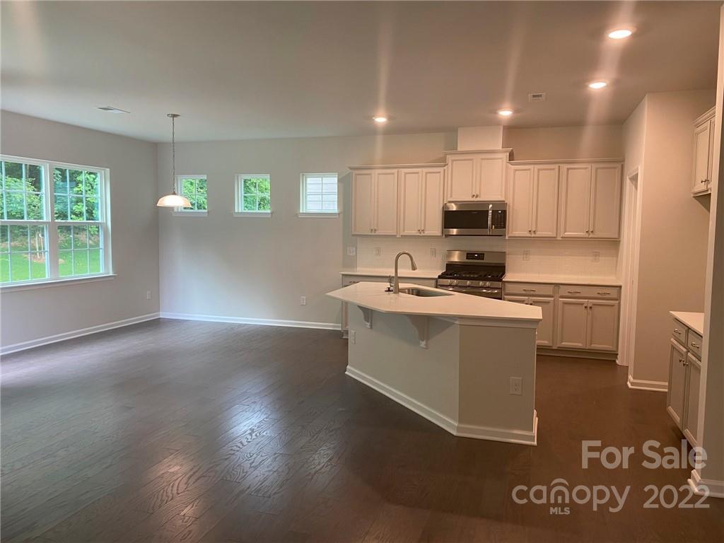 4043 Oakmere Road, Unit 953 Waxhaw, NC 28173 - Photo 8 of 21 a kitchen with kitchen island granite countertop a sink cabinets and stainless steel appliances
