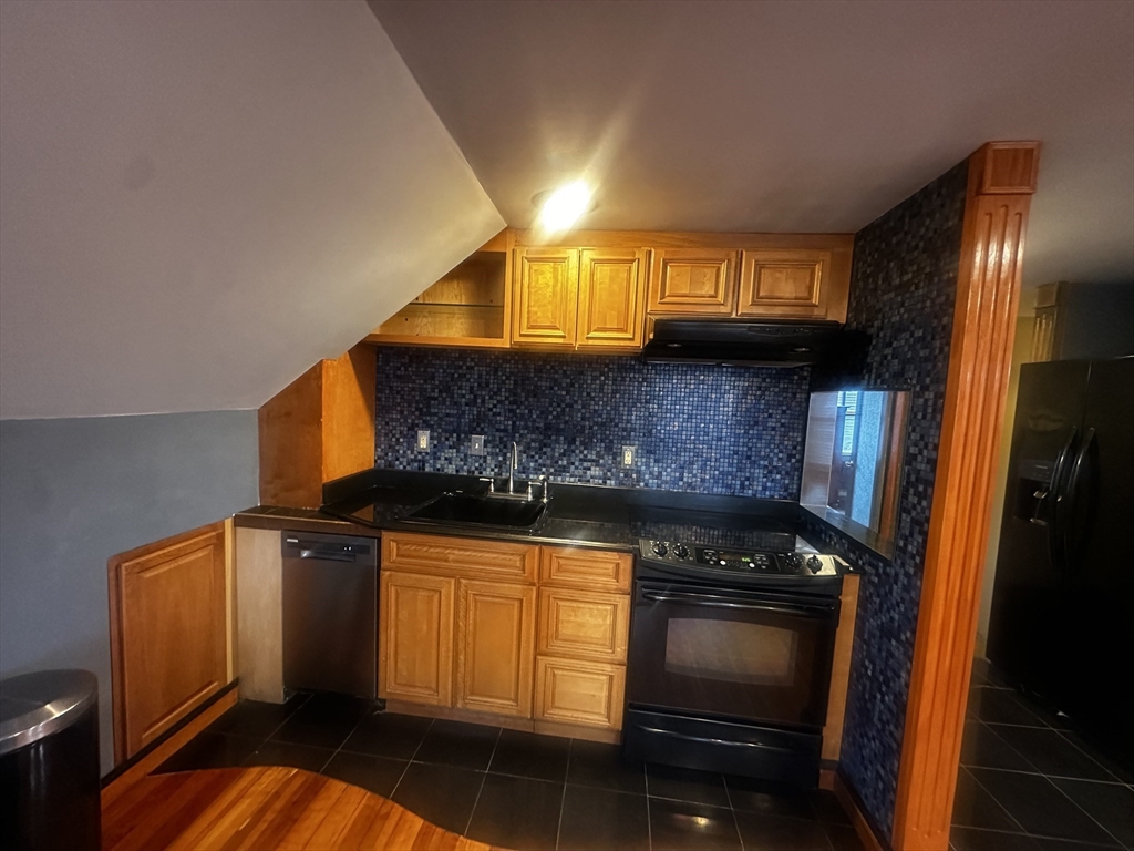 1034 North Main Street, Unit 2 Randolph, MA 02368 - Photo 11 of 14 a kitchen with granite countertop white cabinets and black appliances