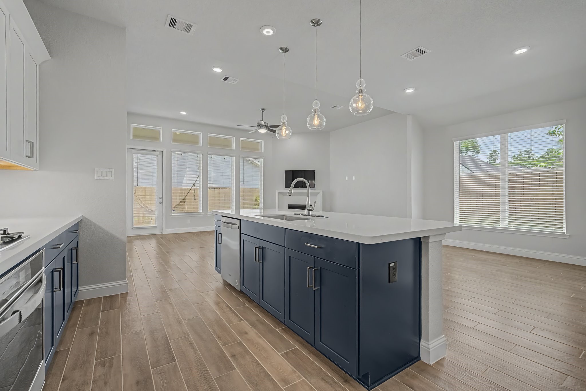 21339 Sierra Point Lane Porter, TX 77365 - Photo 7 of 36 Modern, open-concept kitchen and living area. It features sleek cabinetry, a large island with pendant lighting, wood-look tile flooring, and ample natural light from large windows and a glass door.