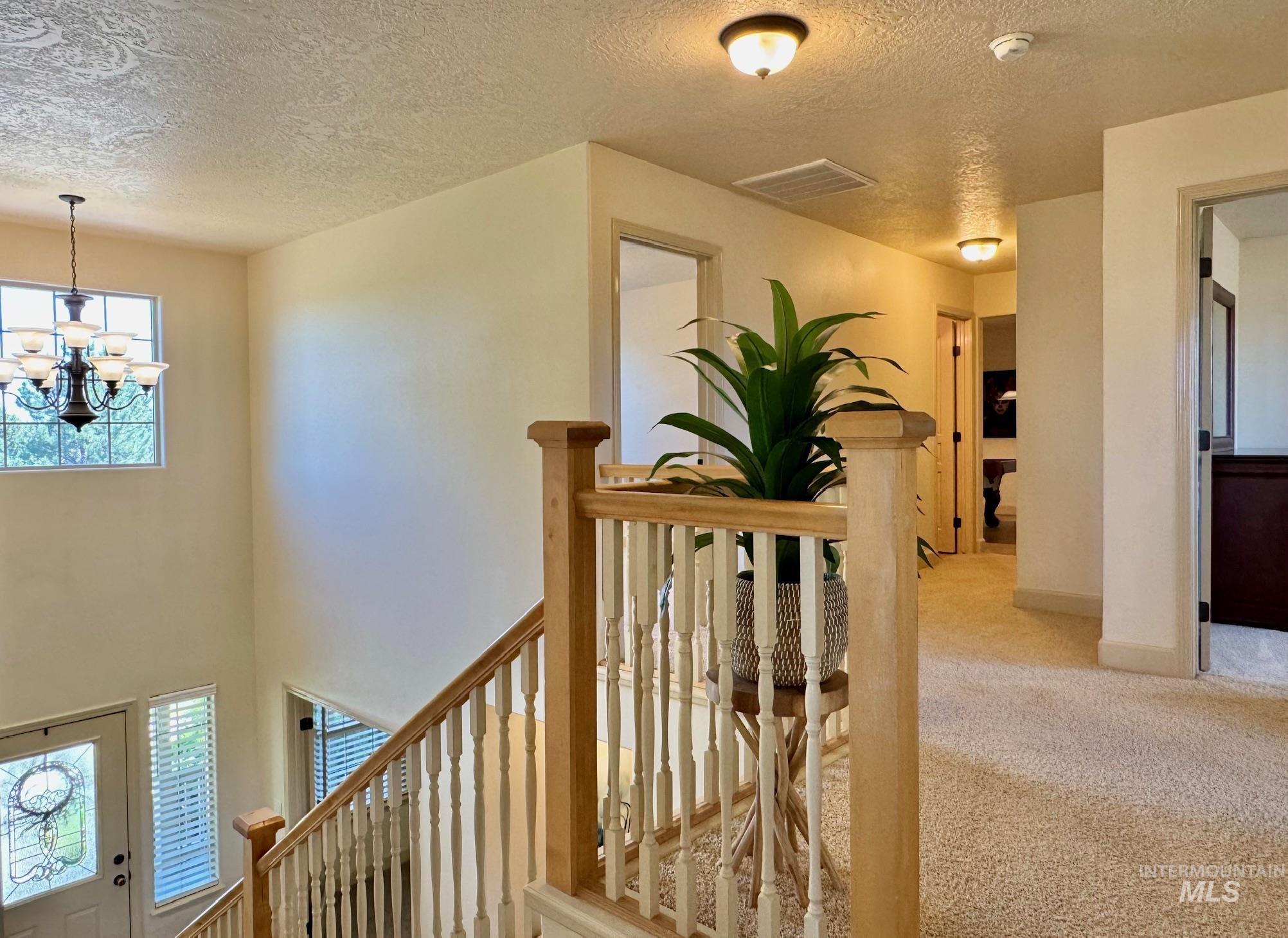9299 Kemp Road Middleton, ID 83644 - Photo 29 of 50 Spacious two-story entryway featuring a decorative chandelier, a clear glass door with leaded glass accents, and a staircase with a natural wood railing and white balusters