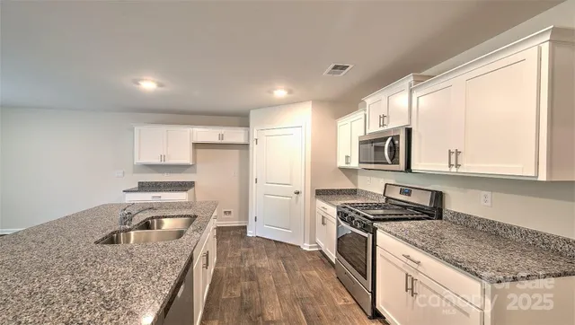 a kitchen with stainless steel appliances granite countertop a stove a sink and a refrigerator