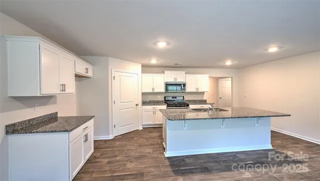 a kitchen with kitchen island granite countertop a sink stove and refrigerator