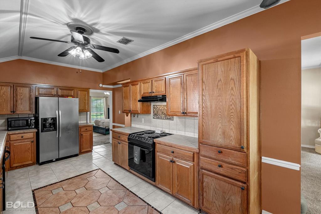 122 Ragan Lane Haughton, LA 71037 - Photo 14 of 34 Kitchen featuring wood-finish cabinetry, tile flooring, and a vaulted ceiling with a ceiling fan