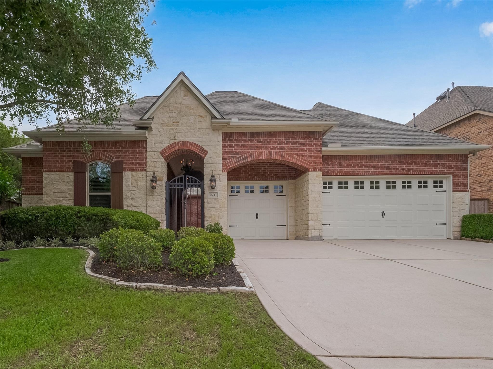 2711 King Point View Lane Spring, TX 77388 - Photo 2 of 48 This home features a charming brick and stone exterior with a gated entryway. It includes a three-car garage, well-maintained landscaping, and a spacious driveway.