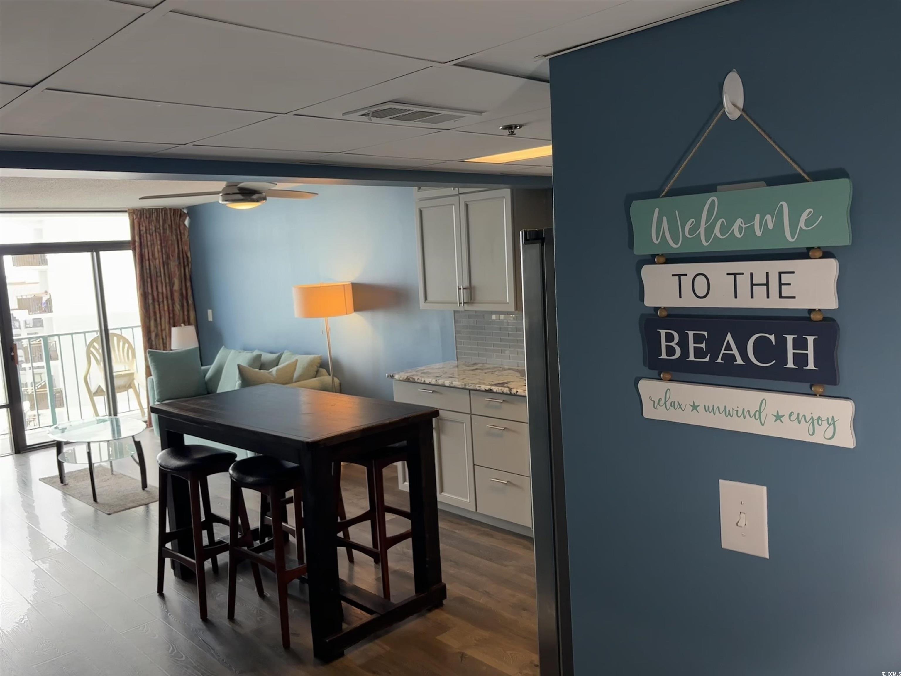 201N 74th Avenue North, Unit 2845/46 Myrtle Beach, SC 29572 - Photo 2 of 9 Kitchen featuring backsplash, floor to ceiling windows, a paneled ceiling, light stone countertops, and white cabinetry