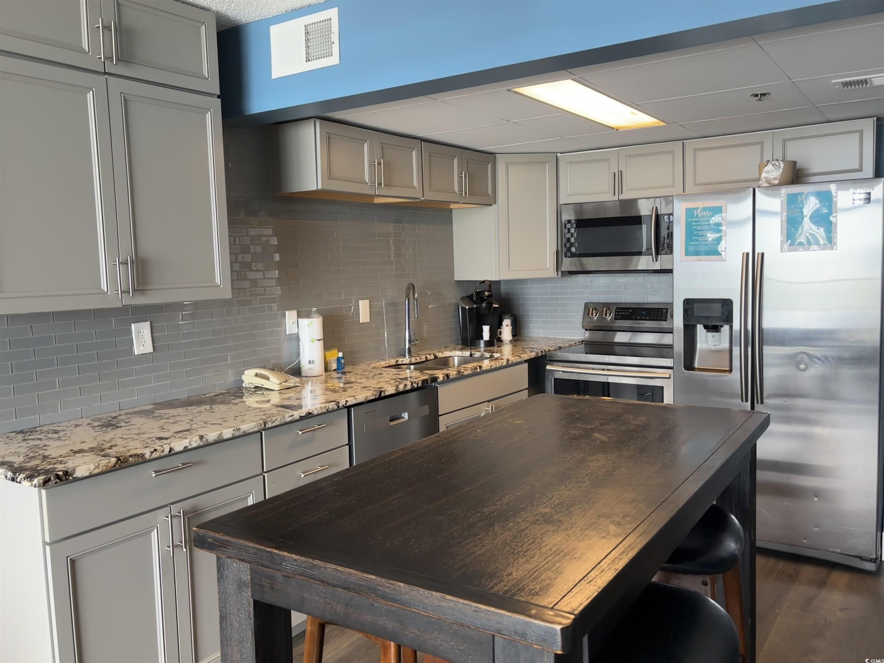 201N 74th Avenue North, Unit 2845/46 Myrtle Beach, SC 29572 - Photo 3 of 9 Kitchen featuring appliances with stainless steel finishes, light stone counters, decorative backsplash, and gray cabinetry