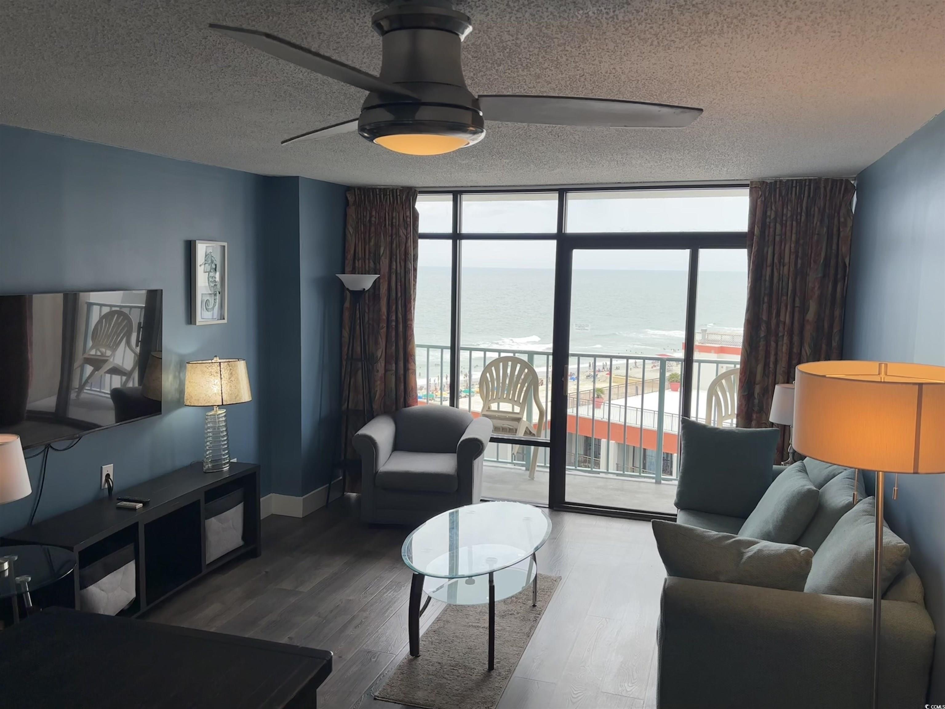 201N 74th Avenue North, Unit 2845/46 Myrtle Beach, SC 29572 - Photo 4 of 9 Living room featuring expansive windows, a water view, a ceiling fan, wood finished floors, and a textured ceiling