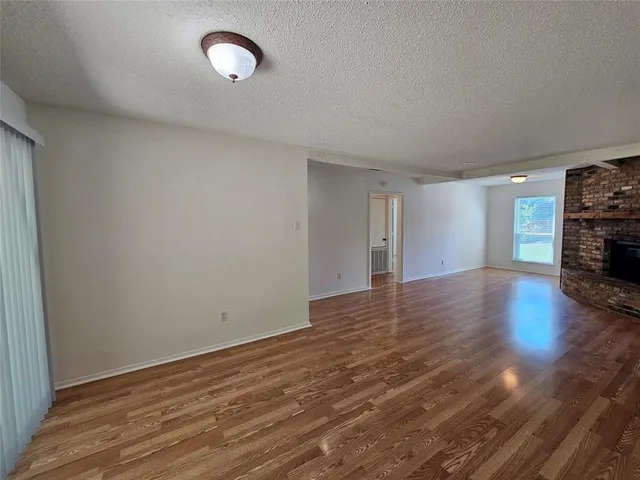 a view of empty room with wooden floor and fireplace