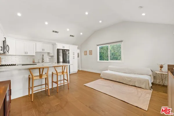 a living room with stainless steel appliances furniture and a kitchen view
