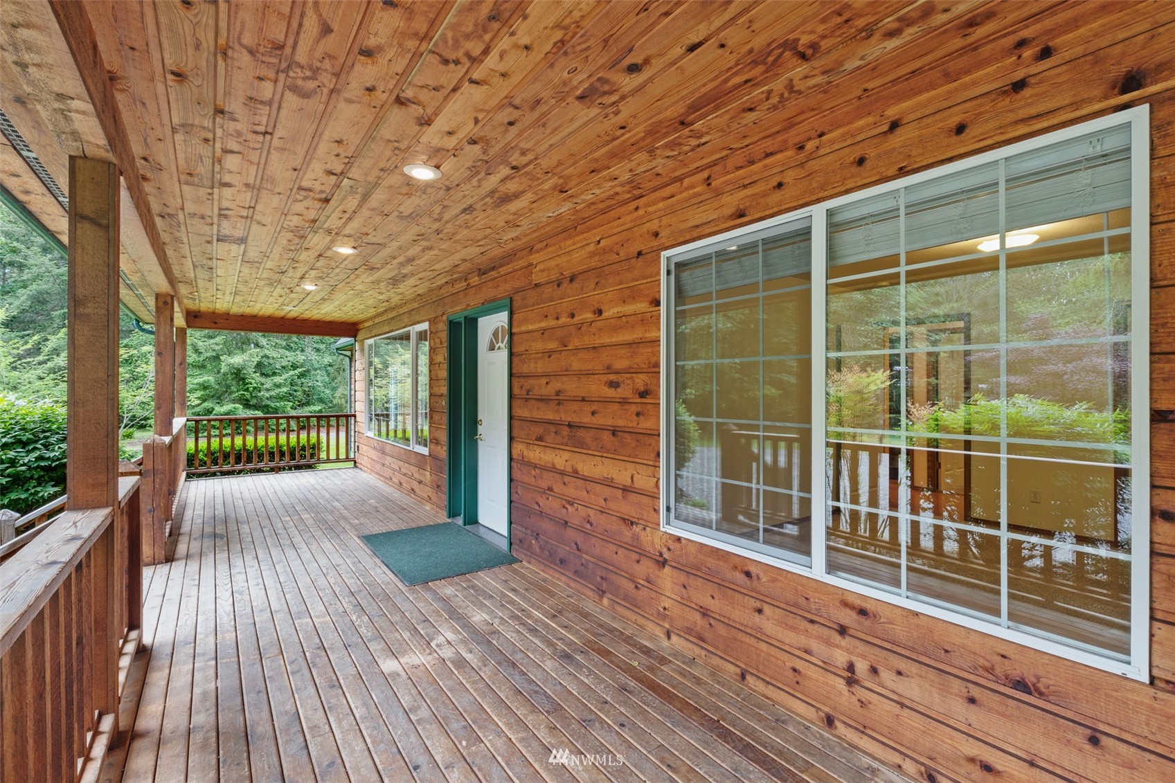 257 Riverside Road Sequim, WA 98382 - Photo 3 of 40 a porch with wooden floor and fence next to a yard