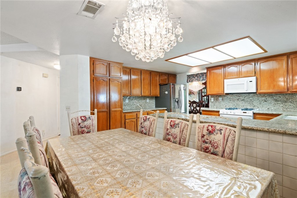 3047 Prado Lane Colton, CA 92324 - Photo 16 of 51 a kitchen with stainless steel appliances kitchen island granite countertop a sink dishwasher a stove a dining table and chairs with wooden floor