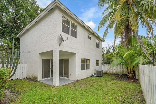 a view of a house with backyard and wooden fence