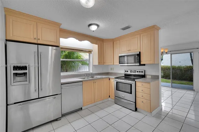 a kitchen with stainless steel appliances granite countertop a refrigerator sink and stove