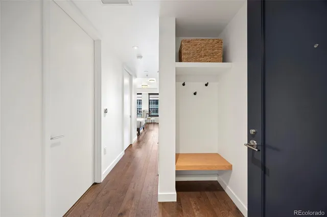 a view of a hallway with wooden floor and a bathroom