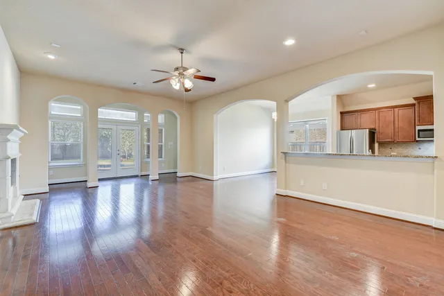 a view of a kitchen and an empty room with wooden floor and a kitchen