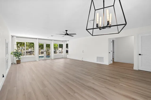 an empty room with wooden floor and ceiling fan