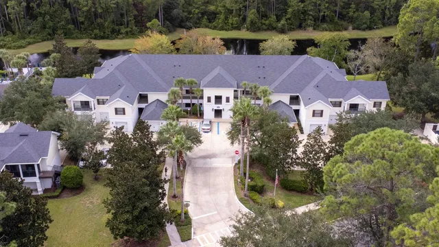 an empty room with chandelier fan and kitchen view