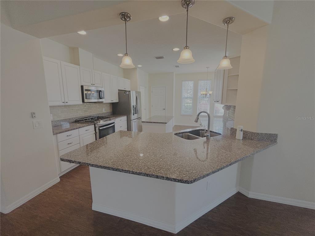 4859 Northwest 35th Ln Road Ocala, FL 34482 - Photo 7 of 30 a kitchen with kitchen island a sink a counter space appliances and cabinets