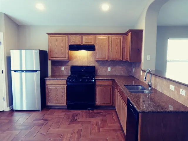 a kitchen with stainless steel appliances granite countertop a refrigerator a sink and a stove