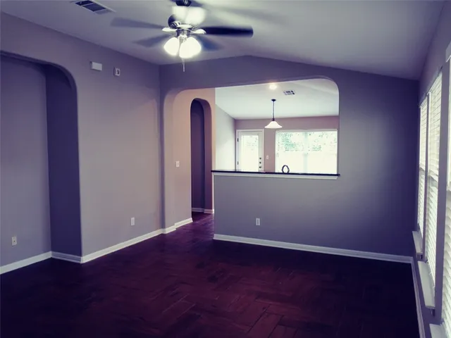 an empty room with a window and a chandelier fan
